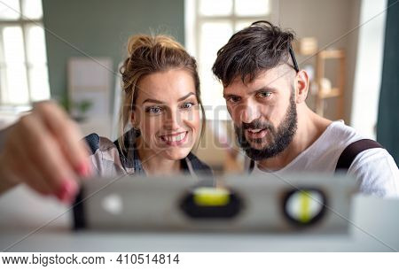 Mid Adults Couple Witj Leveler Indoors At Home, Relocation And Diy Concept.