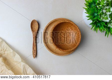 Wooden Utensils On The Kitchen Table. Round Wooden Plates, A Wooden Spoon, A Green Plant. The Concep