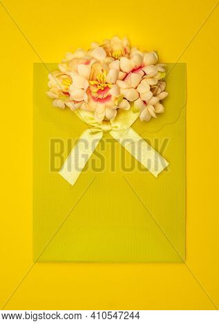 Yellow Gift Bag With Yellow Ribbon And Beautiful Flowers On Top.