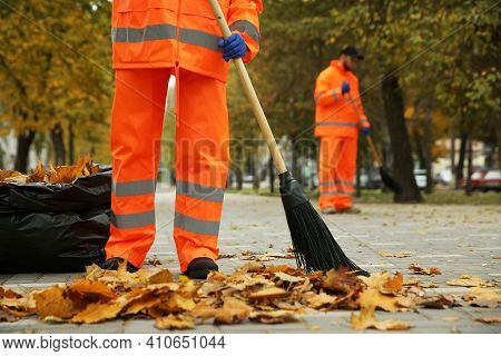 Street Cleaners Sweeping Fallen Leaves Outdoors On Autumn Day, Closeup