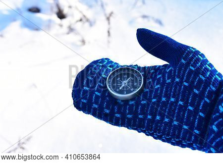 Compass In Hand On Snow Background. Orientation On The Terrain In The Forest In Winter Time. Map Rea