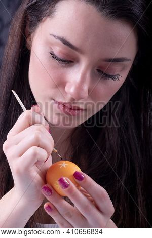 Portrait Of A Beautiful Young Sexy Focused On Work Woman Paints An Orange Easter Egg According To So