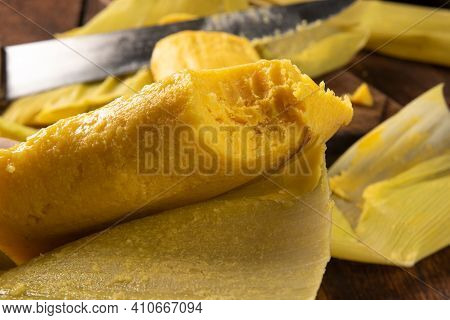 Pamonha, Brazilian Corn Food, Called Pamonha. On A Rustic Table With Knife And Old Corn Grater, Low