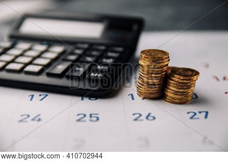 Calendar, Calculator And Stack Of Coins In A Office