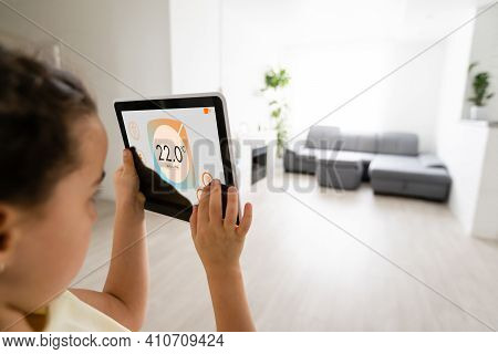 Shot Of Little Girl Using A Domotic System With Her Digital Tablet While Standing At Home.