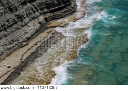 Defocused Beautiful Wild Beach At The Foot Of The Rocks In Sosnovka Camping. Close-up View Of Waves 