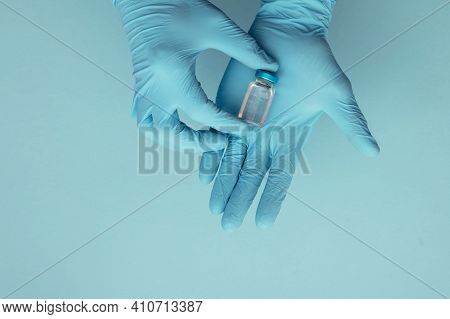 Doctor Or Nurse Wearing Blue Surgical Gloves Holding A Single Vaccine Dose