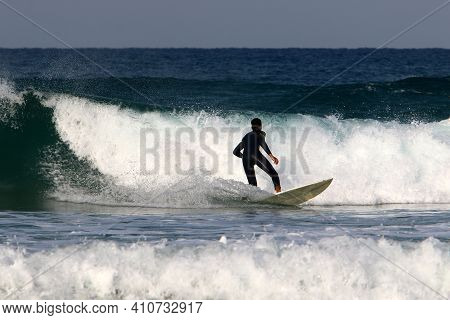 Surfing High Waves In The Mediterranean Sea In Northern Israel. Gliding Along The Crest Of A Large S