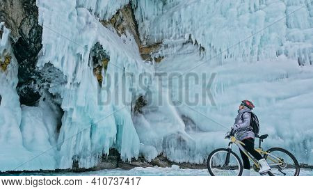 Woman Is Riding Bicycle Near The Ice Grotto. The Rock With Ice C