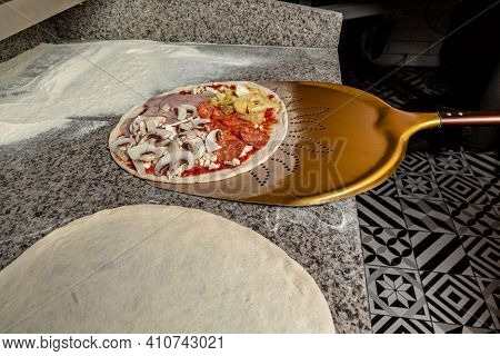 Chef Taking Raw Pizza On Metal Shovel For Baking In The Oven. Traditional Way Baked Wood Fired Oven 