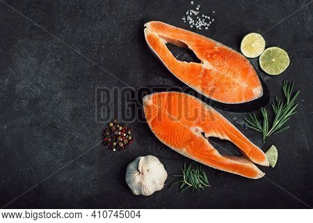 Two Raw Salmon Steaks On A Black Background