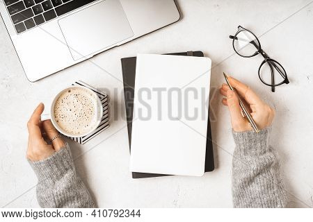 Top View Woman Hands With Blank Paper Notebook, Leaf, Laptop Keyboard, Cup Of Coffee, Glasses And Pe