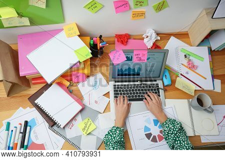 Woman Using Laptop At Messy Table, Top View. Concept Of Being Overwhelmed By Work