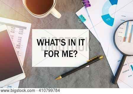 What's In It For Me Is Written In A Document On The Office Desk With Office Accessories, Coffee, Dia