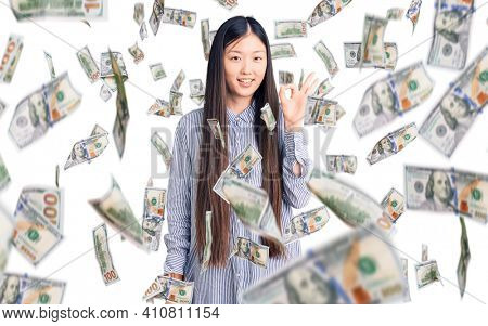 Young beautiful chinese woman wearing casual shirt smiling positive doing ok sign with hand and fingers. successful expression.