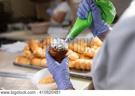 A Roll Of Sweet Puff Pastry And The Hands Of A Pastry Chef Spread The Cream From A Pastry Bag. Bakin