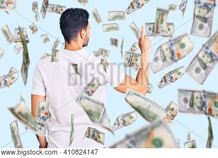 Young handsome hispanic man wearing casual clothes posing backwards pointing ahead with finger hand