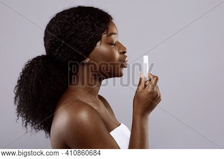 Attractive Black Woman Holding Hygienic Lip Balm In Hand, Standing Over Gray Background, Beautiful A