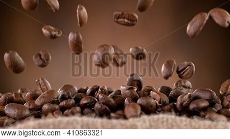 Falling Roasted Coffee Beans into Jute Bag, close-up.