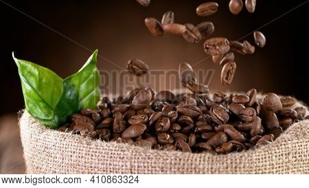 Falling Roasted Coffee Beans into Jute Bag, close-up.