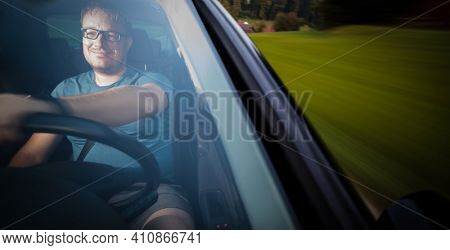 Handsome young driver driving hic car fast yet safely on the road