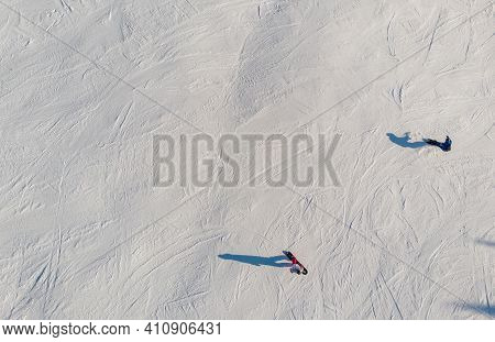 Snowboarders And Skiers Drive Down Ski Slope In Winter Through Fresh Snow, Areal Top View