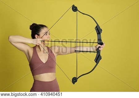 Woman With Bow And Arrow Practicing Archery On Yellow Background