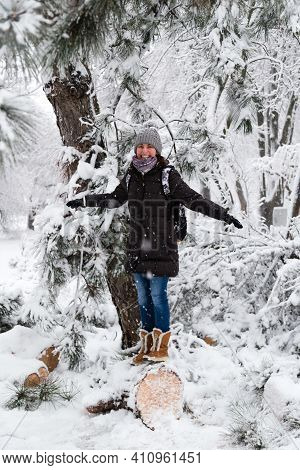 Smiling Young Woman Standing On Fallen Tree After Sleet Load And Snow In A Snow-covered Winter Park.