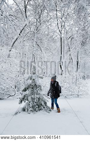 Young Smiling Woman Standing Near To A Small Fir Tree In A Snow-covered Winter Forest. Snowy Winter