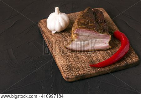 A Piece Of Baked Meat With Layers Of Bacon, Cut From The Bottom Of A Pork Carcass On The Black Backg