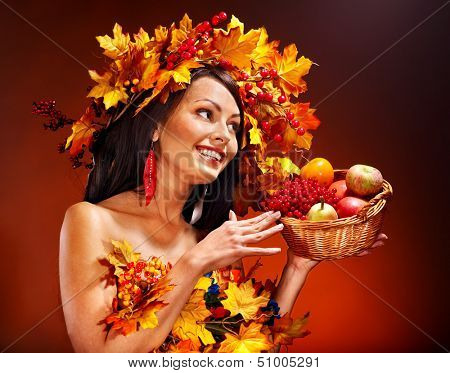 Woman holding autumn basket with fruit and vegetable.
