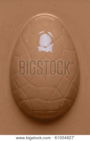 Smooth melted milk chocolate poured over an Easter egg 