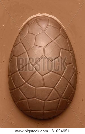 Chocolate Easter egg emerging from smooth melted milk chocolate