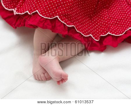 Newborn baby girl feet in red dress