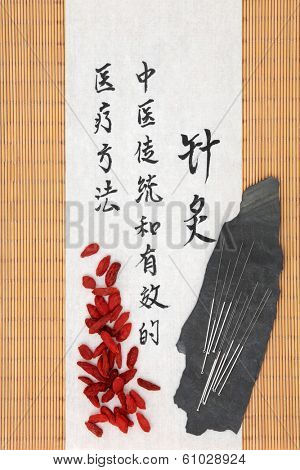 Acupuncture needles and mandarin script on rice paper over bamboo with wolfberry fruit.  