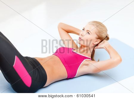 fitness and exercice concept - beautiful sporty woman doing exercise on the floor