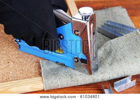 Fastening fabric and board using construction stapler 