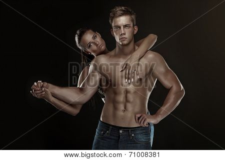Sexy Couple, Beautiful Woman Holding A Muscular Man Isolated On A Black Background