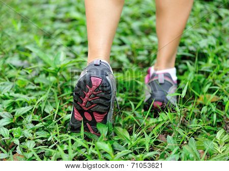 young woman runner legs on geen grass