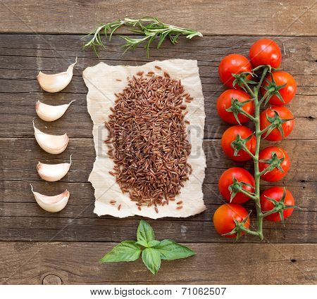 Organic Red Rice, Tomatoes, Garlic And Herbs On Wooden Background
