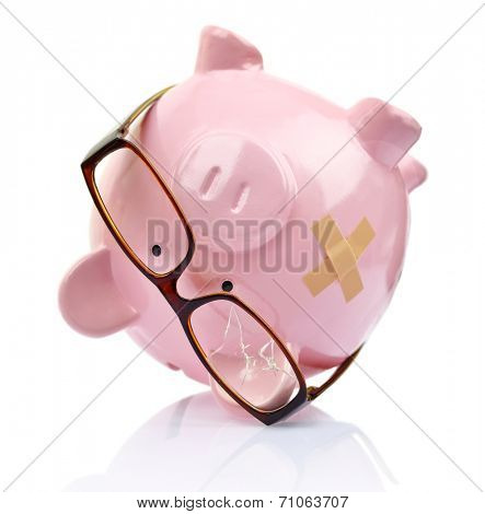 Piggy bank with broken eyeglasses and bandage upside down 