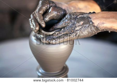 Hands of a potter, creating an earthen jar