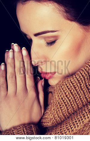 Young woman praying with closed eyes.