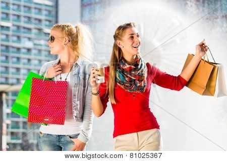 Women shopping in city with bags having coffee and bags in hands