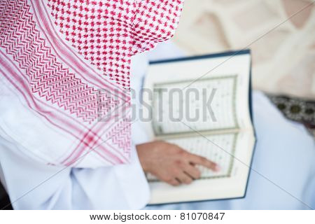 Young Arabic Muslim man reading Koran and praying