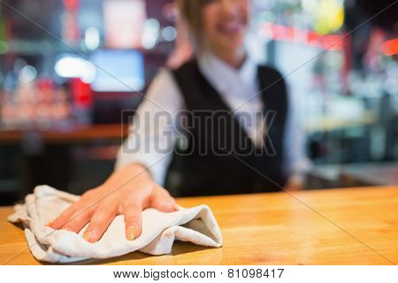 Pretty barmaid wiping down bar in a bar