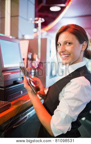 Pretty barmaid using touchscreen till in a bar