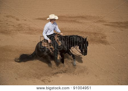 Cowboy Sliding To A Stop On A Black Horse