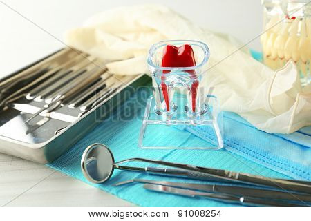 White fake teeth, prosthesis and dental instruments on table background