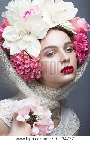Beautiful girl in a headscarf in the Russian style, with flowers on the head and red lips.